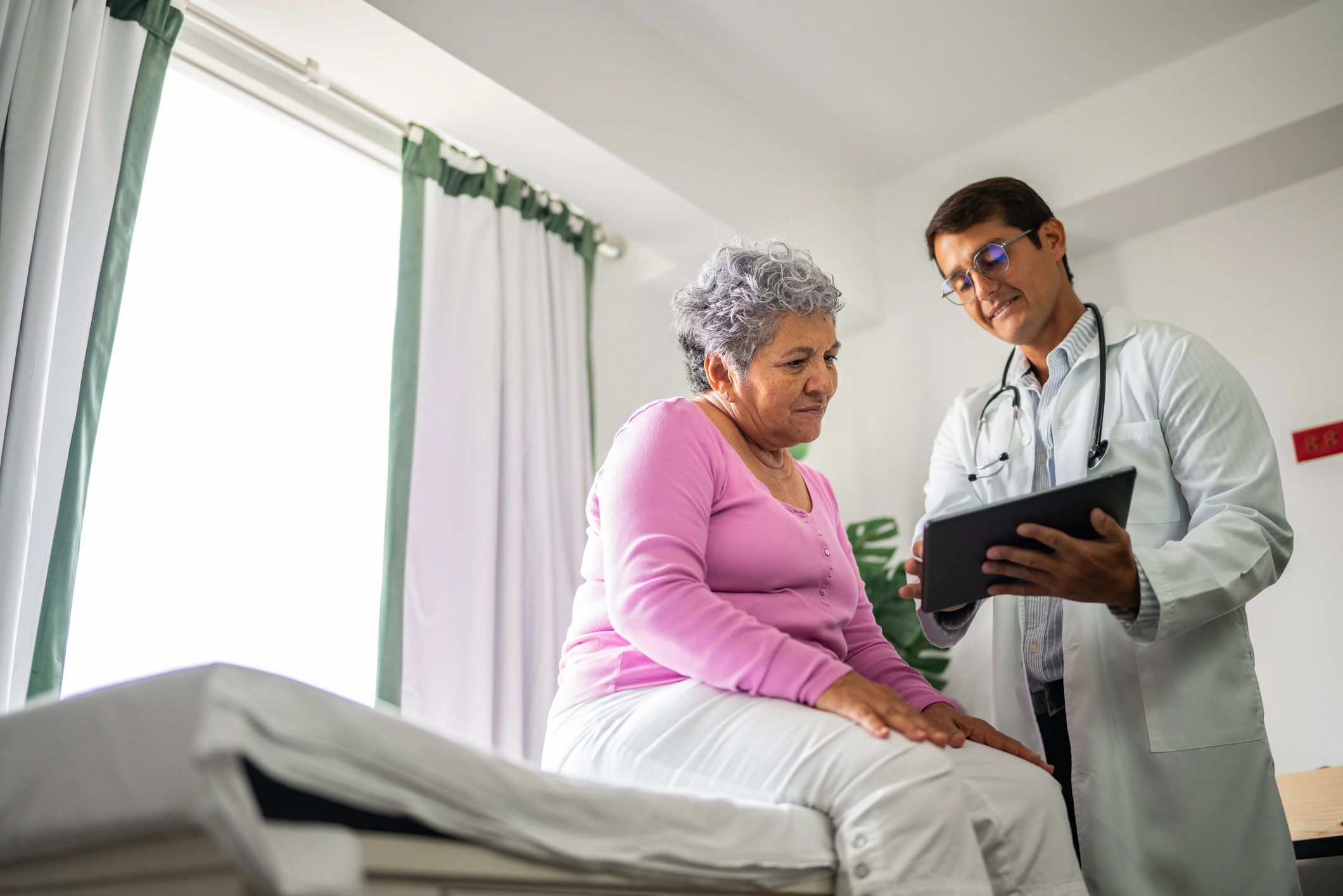 Doctor showing tablet and talking to patient during consultation