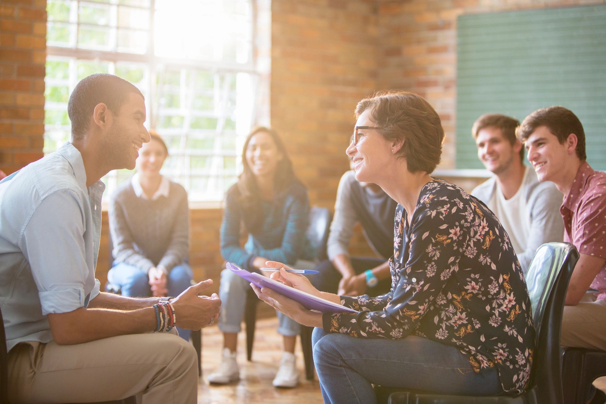 Group therapy session with participants listening and speaking